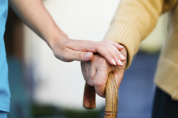 Kobieta trzyma dłoń na ręce starszej osoby