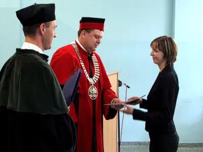 Władze uczelni wręczają list gratulacyjny jednej ze studentek