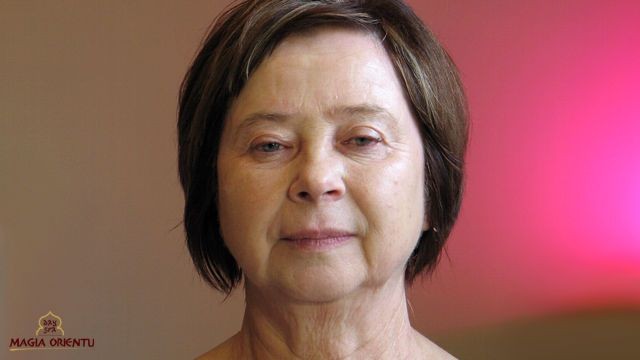 Twarz bez makijażu dojrzałej kobiety. Kosmetyczka wskazuje na zmarszczki mimiczne i opadające fałdy powiek oraz mniej wyraziste brwi i rzęsy u osób starszych. To elementy, na które należy zwrócić uwagę przy robieniu makijażu.