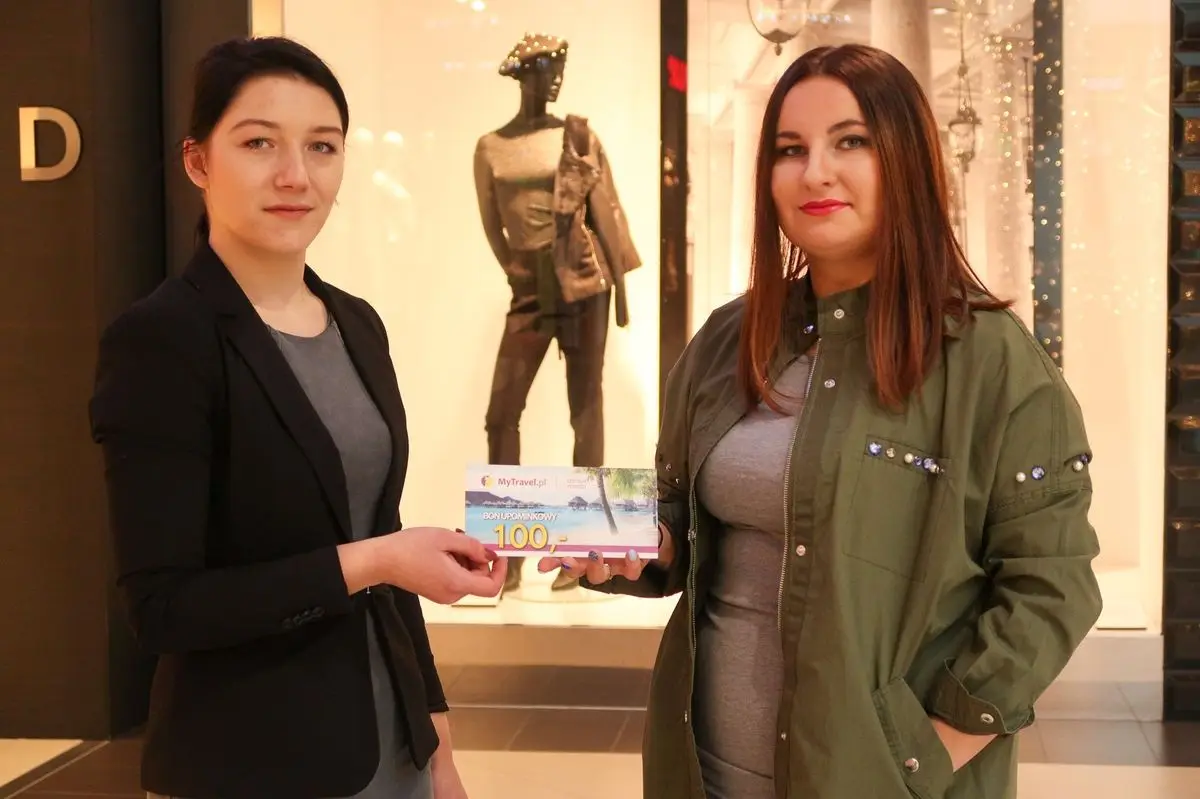 Przedstawicielka biura podróży MyTravel wręcza bon o wartości 100 zł