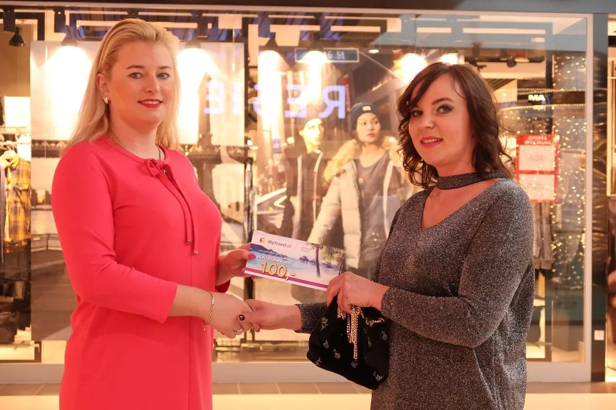Przedstawicielka biura podróży MyTravel wręcza bon o wartości 100 zł