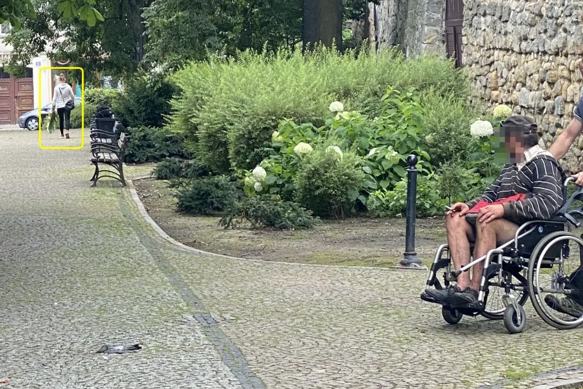Kobieta odchodząca z kwiatami spod pomniku PW