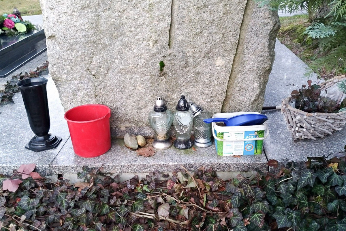 Nagrobek zadbany, a za nim schowane brudne szmaty i śmieci