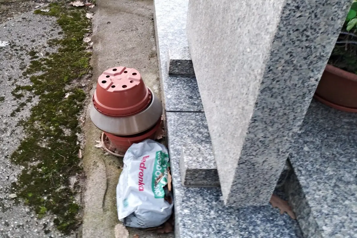 Nagrobek zadbany, a za nim schowane brudne szmaty i śmieci
