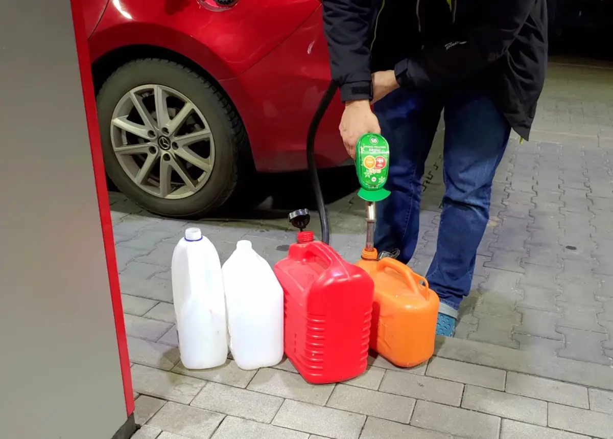Mężczyzna tankuje benzynę do pojemników