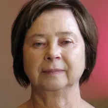 Zobacz zdjęcie: Twarz bez makijażu dojrzałej kobiety. Kosmetyczka wskazuje na zmarszczki mimiczne i opadające fałdy powiek oraz mniej wyraziste brwi i rzęsy u osób starszych. To elementy, na które należy zwrócić uwagę przy robieniu makijażu.